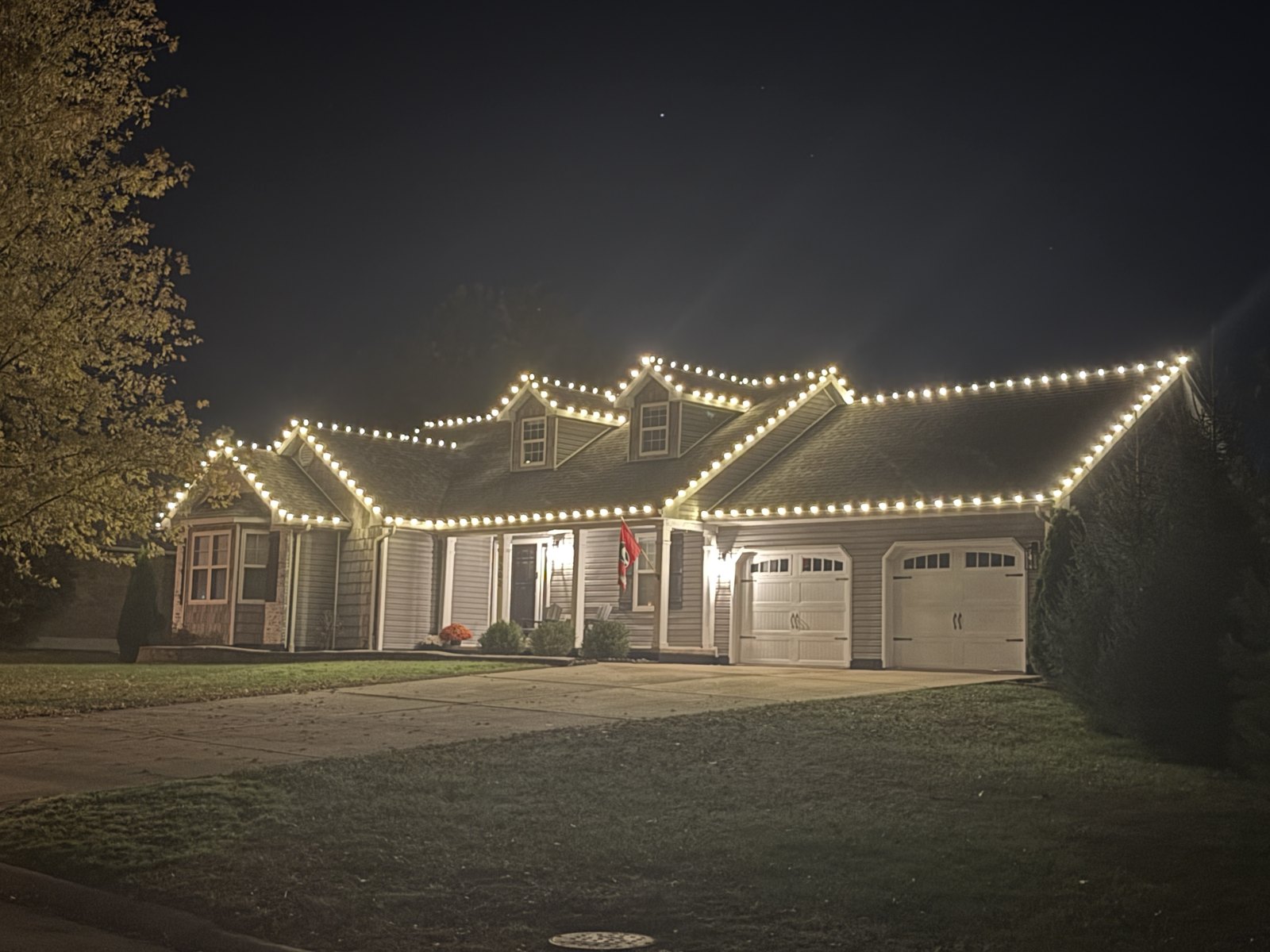 A brick home with warm white Christmas roofline lighting