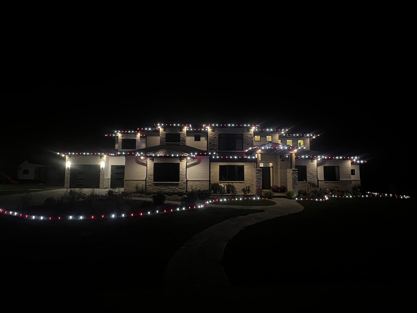 Christmas roofline lighting across a large home at night
